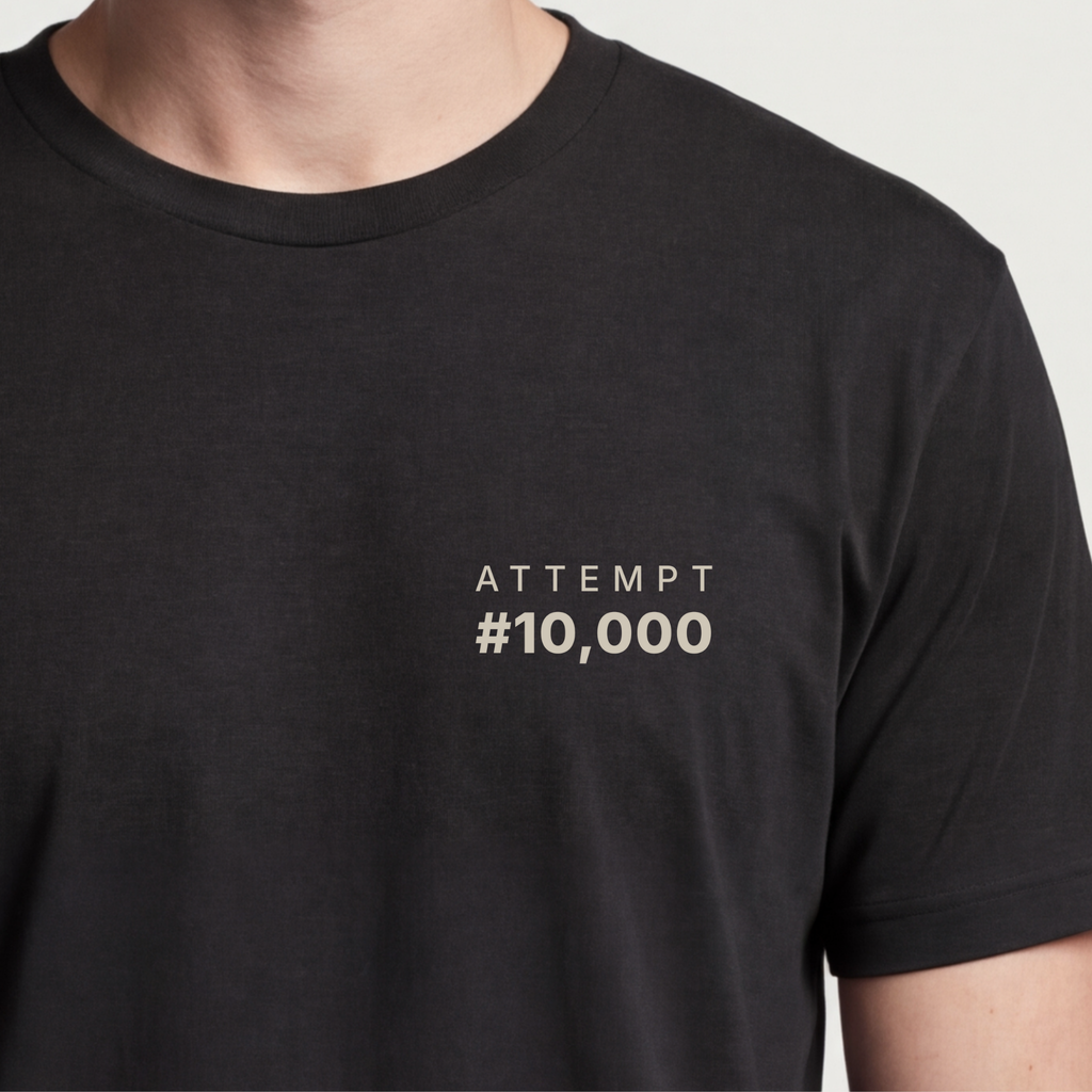 Founder Threads | Attempt #10,000 Tee. System Black grit and resilience gear for tech founders. Hero crop close-up.