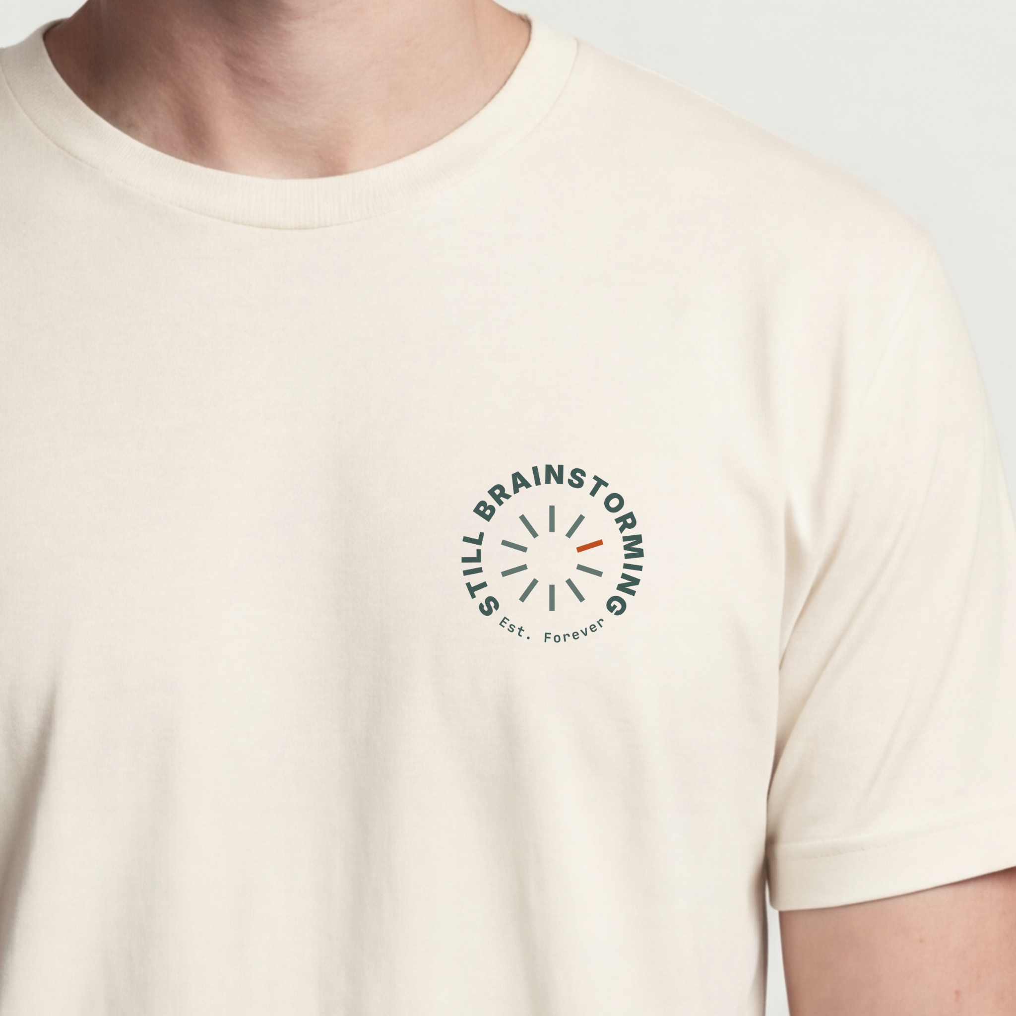 Founder Threads | Still Brainstorming Technical Tee - Natural Bone - Hero Crop. Minimalist typography for software engineers and builders.