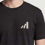 Founder Threads | First Domino Tee. System Black catalyst gear for SaaS founders and tech builders. Hero crop view.