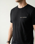 Person wearing a black t-shirt with 'Vibe + Revenue' text on a plain background
